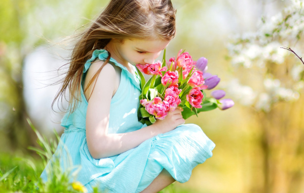 Красивая девочка в голубом платье с букетом тюльпанов