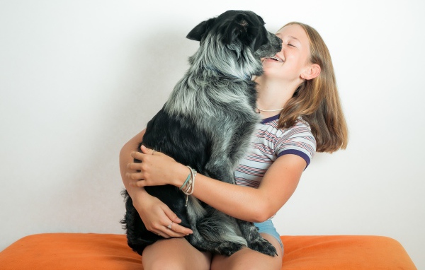 Веселая девочка с собакой в руках 