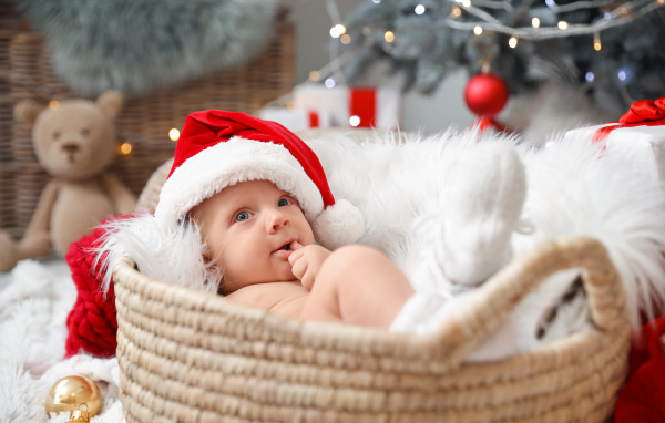 Милый малыш в шапке Санта Клауса лежит в корзине