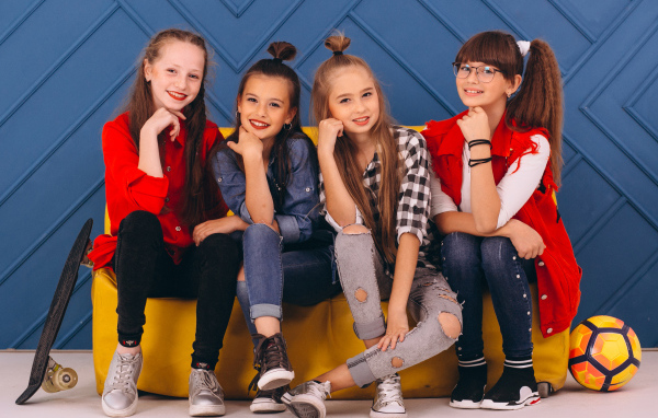 Четыре модных девочки сидят на диване 