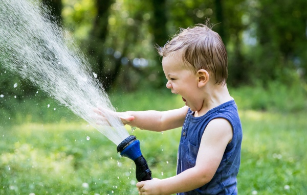 Смешной маленький мальчик играет с водой 