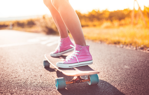 Девочка в розовых кедах едет на скейтборде