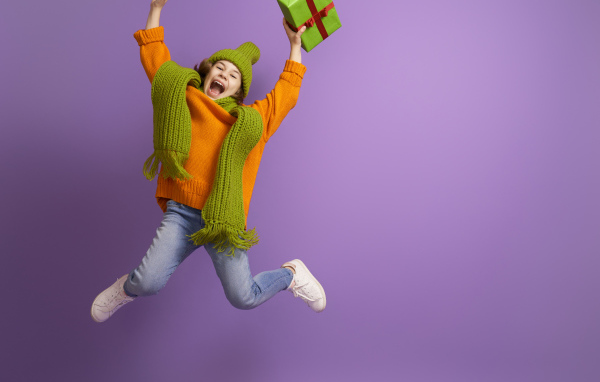 Счастливая девочка с подарком в руке на фиолетовом фоне