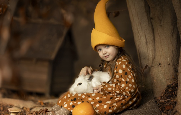 Маленькая смешная девочка в колпаке с кроликом