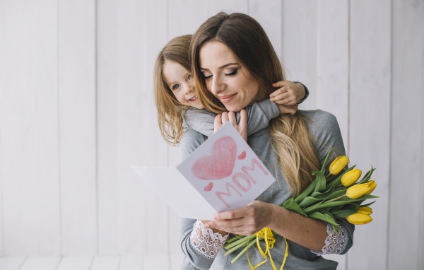 Маленькая девочка подарила маме открытку и букет тюльпанов