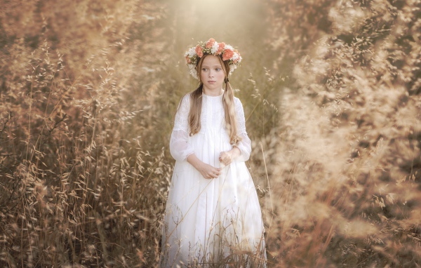 Маленькая девочка в белом платье с венком на голове 