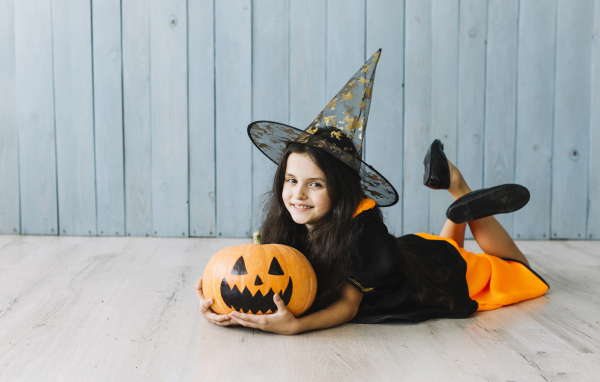 Маленькая девочка в костюме ведьмы с тыквой на Хэллоуин