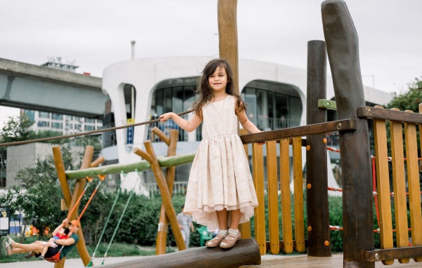 Маленькая девочка стоит на детской площадке 