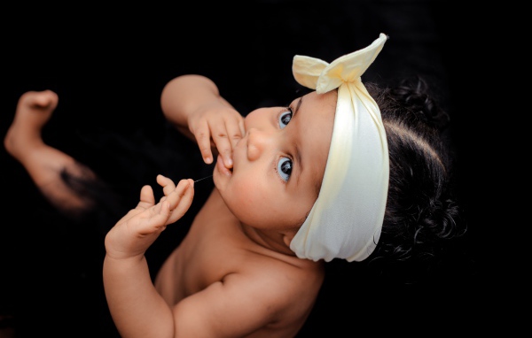 Маленькая девочка с повязкой на голове на черном фоне