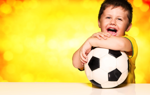 Маленький довольный мальчик с футбольным мячом