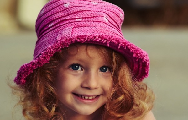 Маленькая улыбающаяся девочка в розовой шляпе