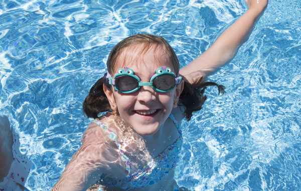 Маленькая улыбающаяся девочка в очках в бассейне 