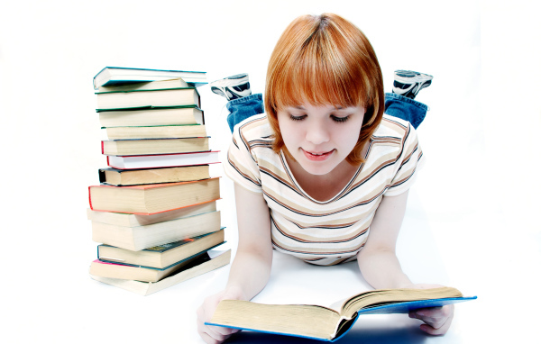 Рыжеволосая девочка школьница читает книги на белом фоне 