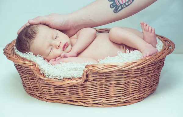 Спящий грудной ребенок в корзине на сером фоне 