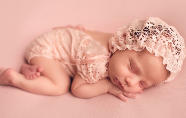 Спящий грудной ребенок в розовом костюме 
