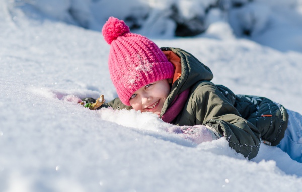 Улыбающаяся девочка лежит на снегу