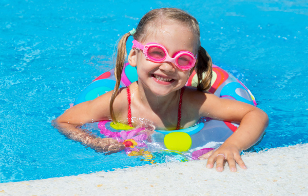 Улыбающаяся девочка с кругом в бассейне 