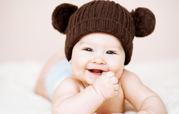 Улыбающийся грудной ребенок в коричневой шапке