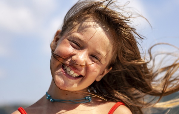 Ветер развивает волосы улыбающейся девочки