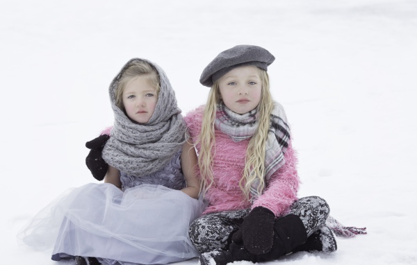 Две маленьких сестры сидят на снегу 