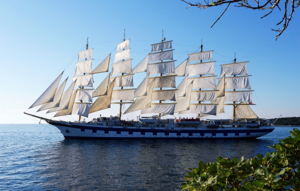 A large ship with white sails is sailing