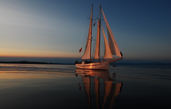 Large yacht with white sails at sunset in the sea