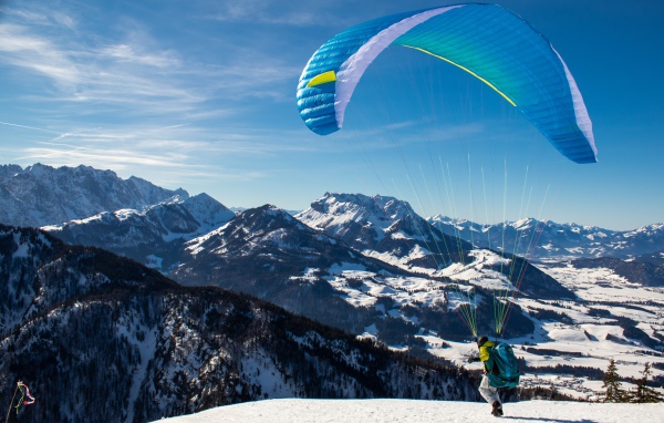 Парапланерист прыгает с горы зимой 