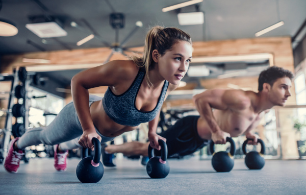 Парень и девушка занимаются с гирями в спортзале 