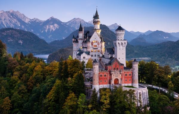 Neuschwanstein Castle in a forest thicket against a backdrop of mountains, Germany