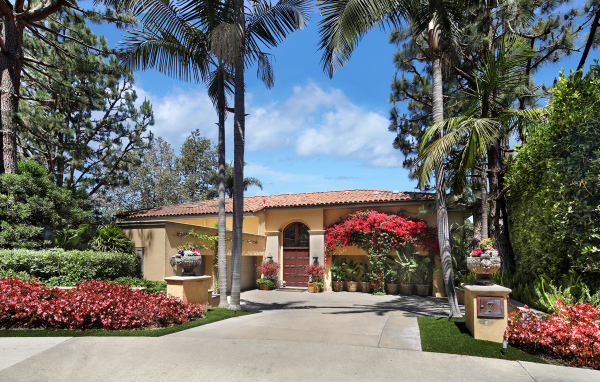 Дом на улице с цветущими кустами и пальмами