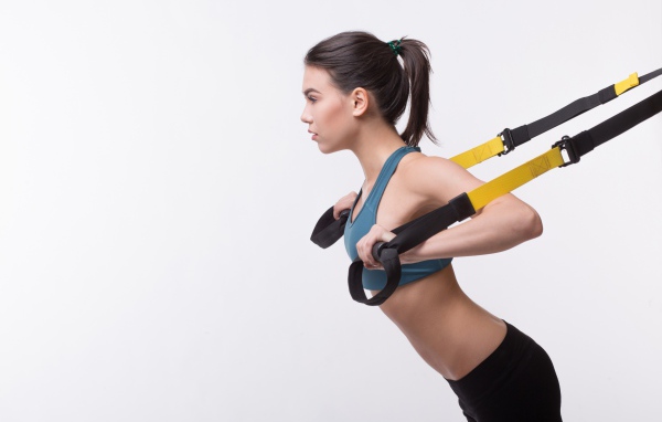 Спортивная девушка занимается в спортзале на белом фоне 