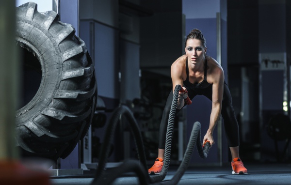 Спортивная девушка занимается с канатами в спортзале 