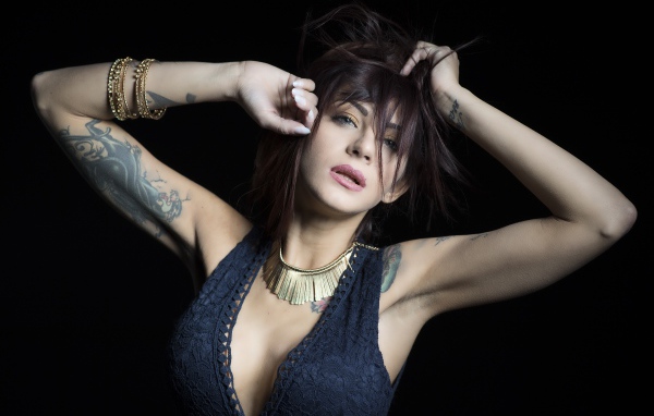 Красивая девушка в черном платье с татуировками на теле 