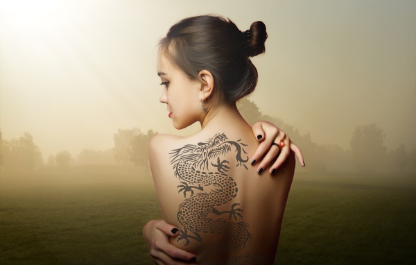 Красивая девушка с татуировкой дракона на спине