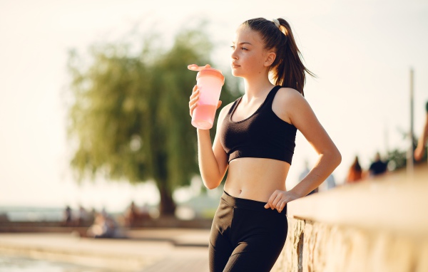 Девушка в черном спортивной форме с водой 