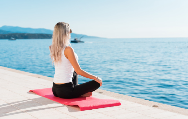 Девушка медитирует на берегу моря 