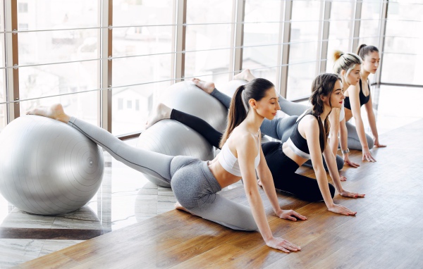 Девушки делают упражнения с фитболом в спортзале