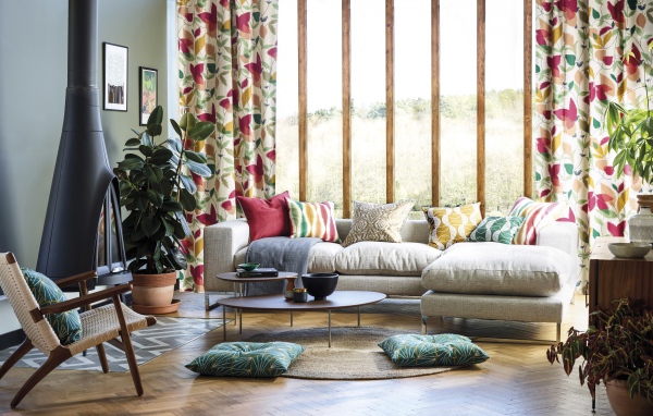 Серый мягкий диван стоит у большого окна в комнате