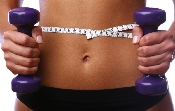 Стройная спортивная девушка с гантелями в руках 