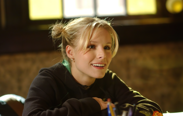 Улыбающаяся актриса Кристен Белл сидит в классе 