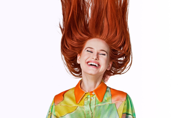 Улыбающаяся актриса Мэделин Петш с рыжими волосами на белом фоне