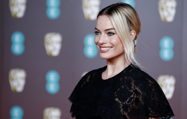 Улыбающаяся актриса Марго Робби в черном платье 