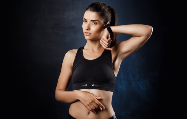 Спортивная девушка в черном костюме с часами на руке