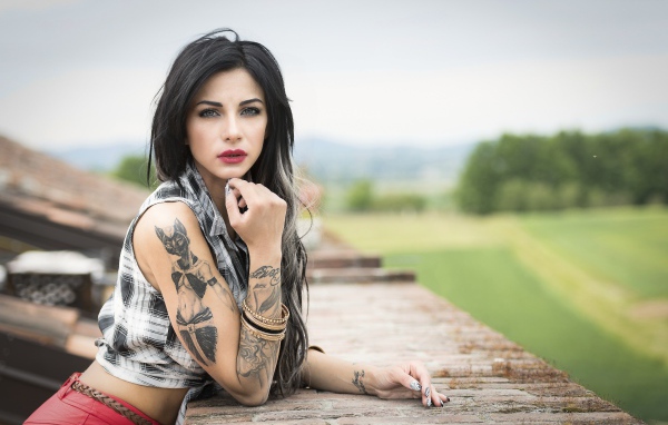 Young brunette girl with tattoos in her arms
