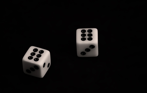 Две белые игральные кости с шестерками на черном фоне