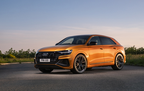 Оранжевый автомобиль Audi SQ8 TFSI 2021 года на фоне неба