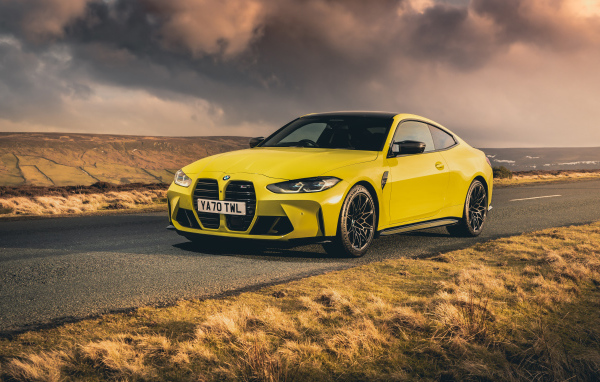 Желтый автомобиль BMW M4 Competition 2021 года на фоне грозового неба