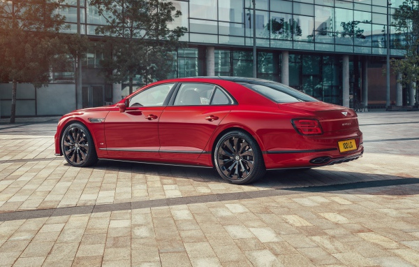 Красный автомобиль Bentley Flying Spur V8 2020 года у здания 