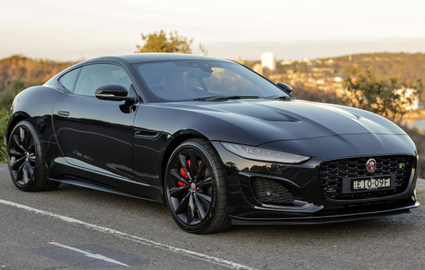 Дорогой черный автомобиль Jaguar F-Type R на дороге