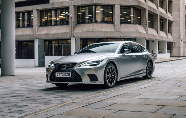 Серебристый автомобиль Lexus LS 500h 2021 года в городе у дома